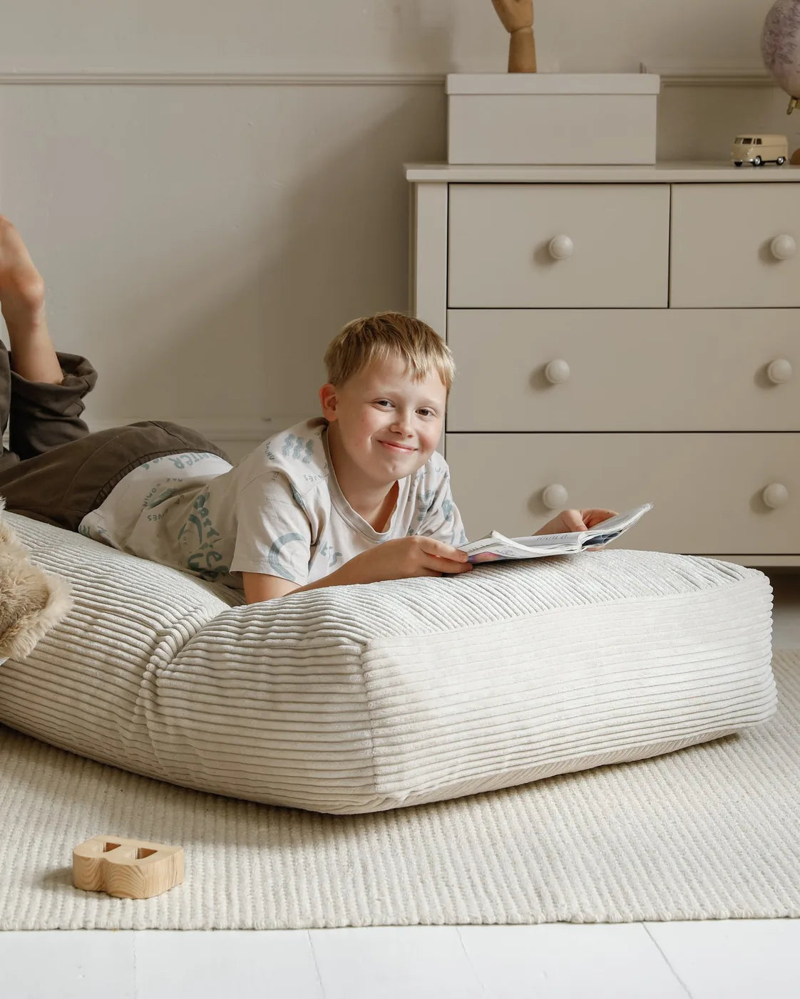 Dziecko stoi na miękkiej pufie Futon Bean Bag w kolorze Vanilla