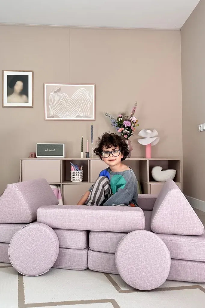 Dziecko siedzi w samochodzie zbudowanym z Play Sofa Original Mini w kolorze Soft Pink
