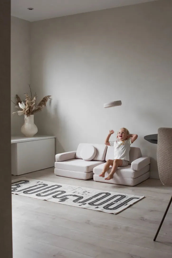 Dziecko odpoczywa na Play Sofa Original Mini w kolorze Soft Beige w pokoju dziennym