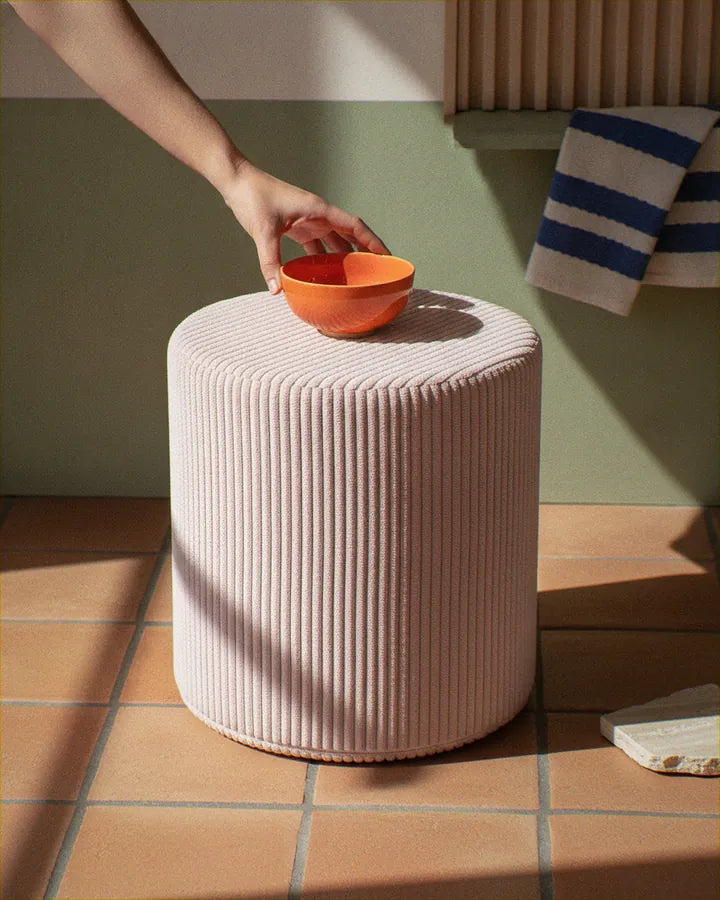 Dłoń stawia miseczkę na pufie Shappy Pouf Corduroy w kolorze Candy