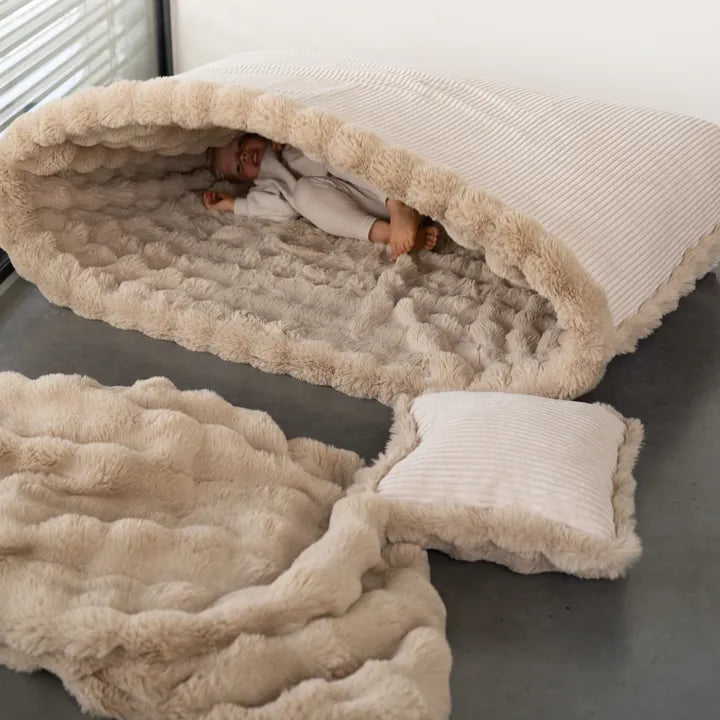Snuggle Bag z dzieckiem w środku, obok Snuggle Blanket i Snuggle Cushion
