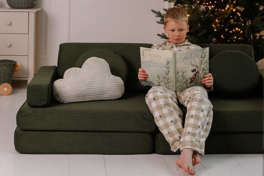 Chłopiec czyta na sofie do zabawy obok poduszki Cloud Cushion