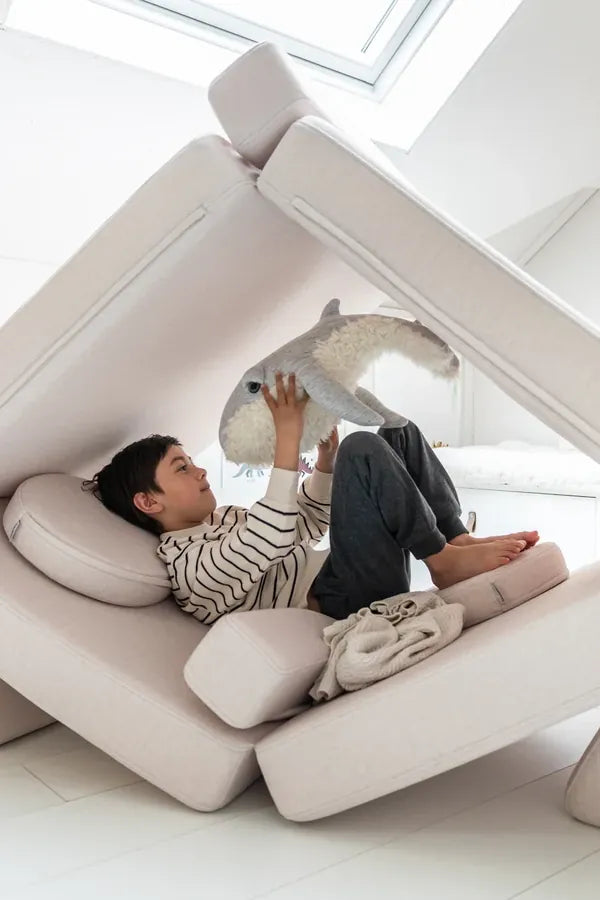 Dziecko odpoczywa w kryjówce zbudowanej z Play Sofa Original w kolorze Soft Beige