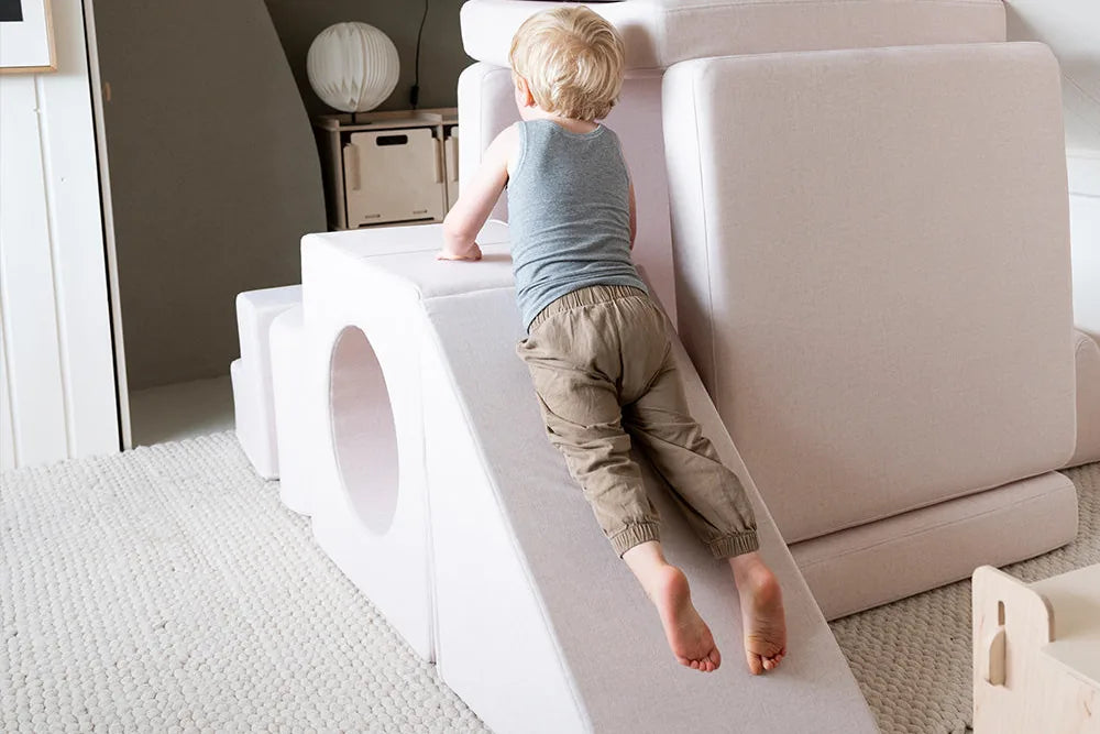 Dziecko wspina się po zjeżdżalni w konstrukcji z zestawu Playset, w pokoju na poddaszu