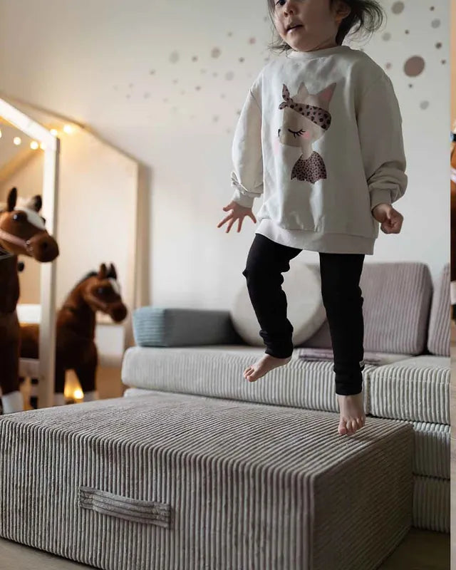 Dziewczynka skacze na Trampoline Pure Corduroy obok Play Sofa