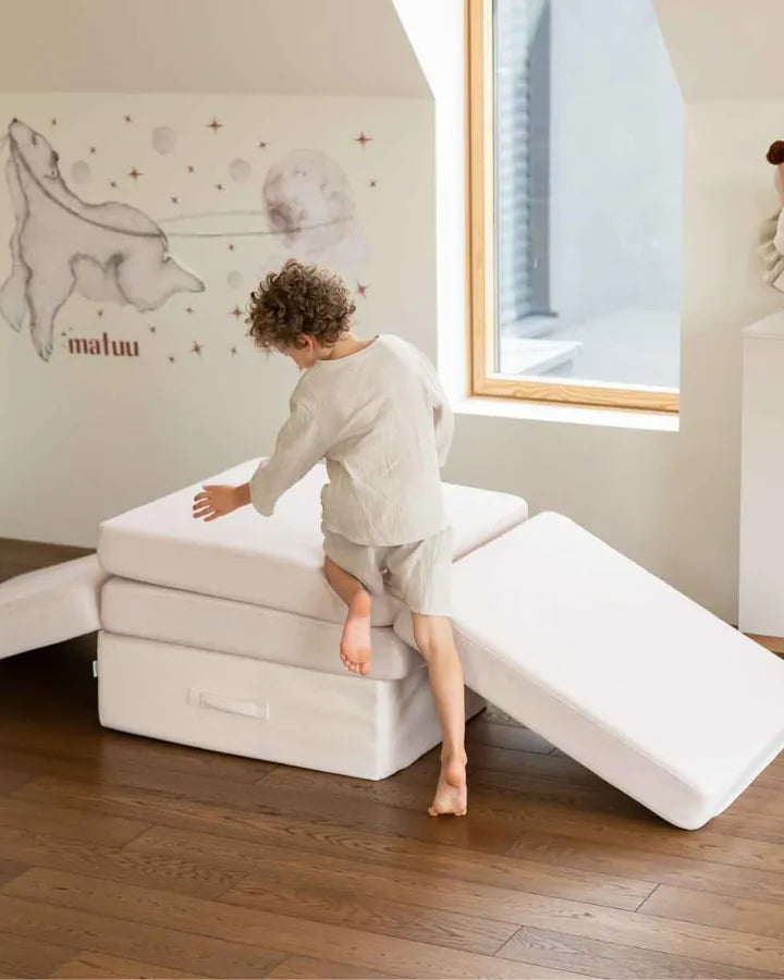 Chłopiec buduje z Trampoline i Play Sofa Original w kolorze Soft Beige