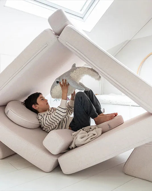 Chłopiec odpoczywa w namiocie zbudowanym z Play Sofa Original w kolorze Soft Beige
