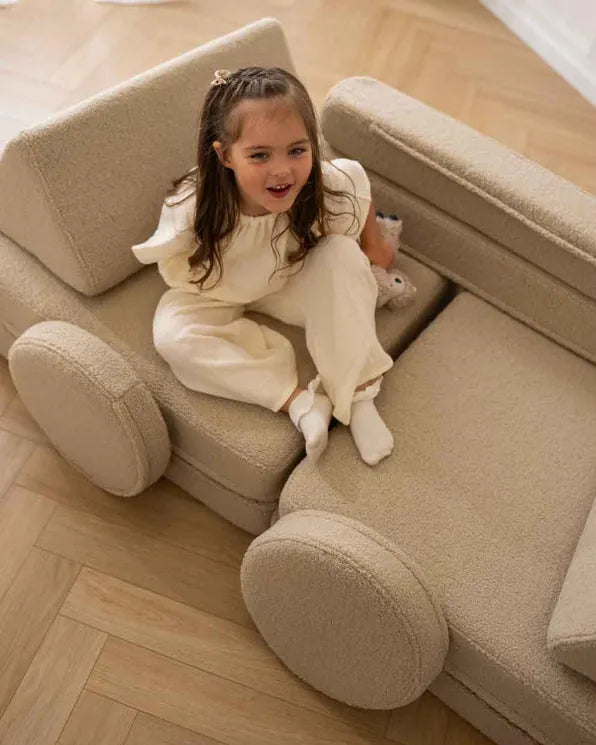 Dziewczynka siedzi na Play Sofa Original Teddy w kolorze Light Beige