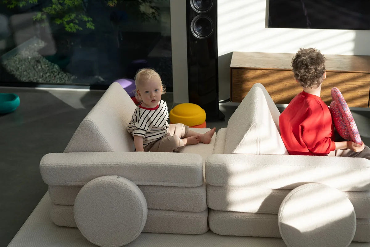 Dwoje dzieci bawi się w samochodzie zbudowanym z Play Sofa Original Teddy w kolorze Soft Cream
