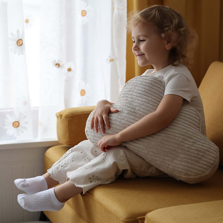 Dziewczynka przytula poduszkę Cloud Cushion na sofie do zabawy
