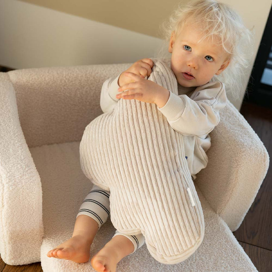 Maluch przytula poduszkę Cloud Cushion w foteliku Lumi Chair