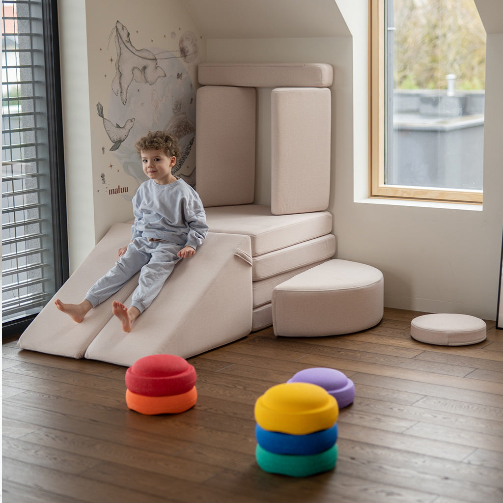 Chłopiec zjeżdża ze Slide w kolorze Soft Beige obok sofy do zabawy