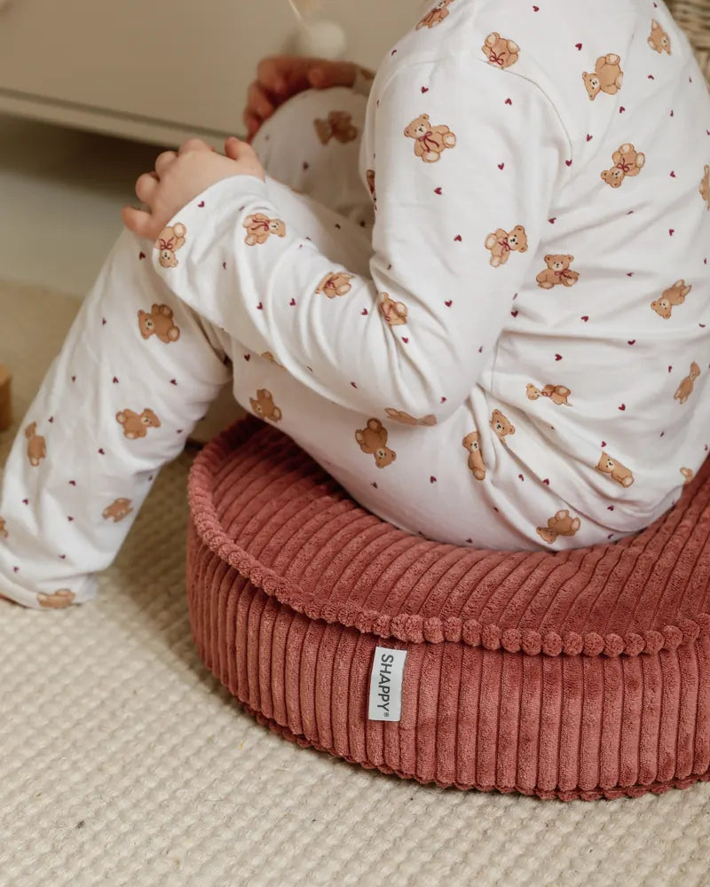 Zbliżenie: dziecko siedzi na pufie Yuka Mini w kolorze Rose