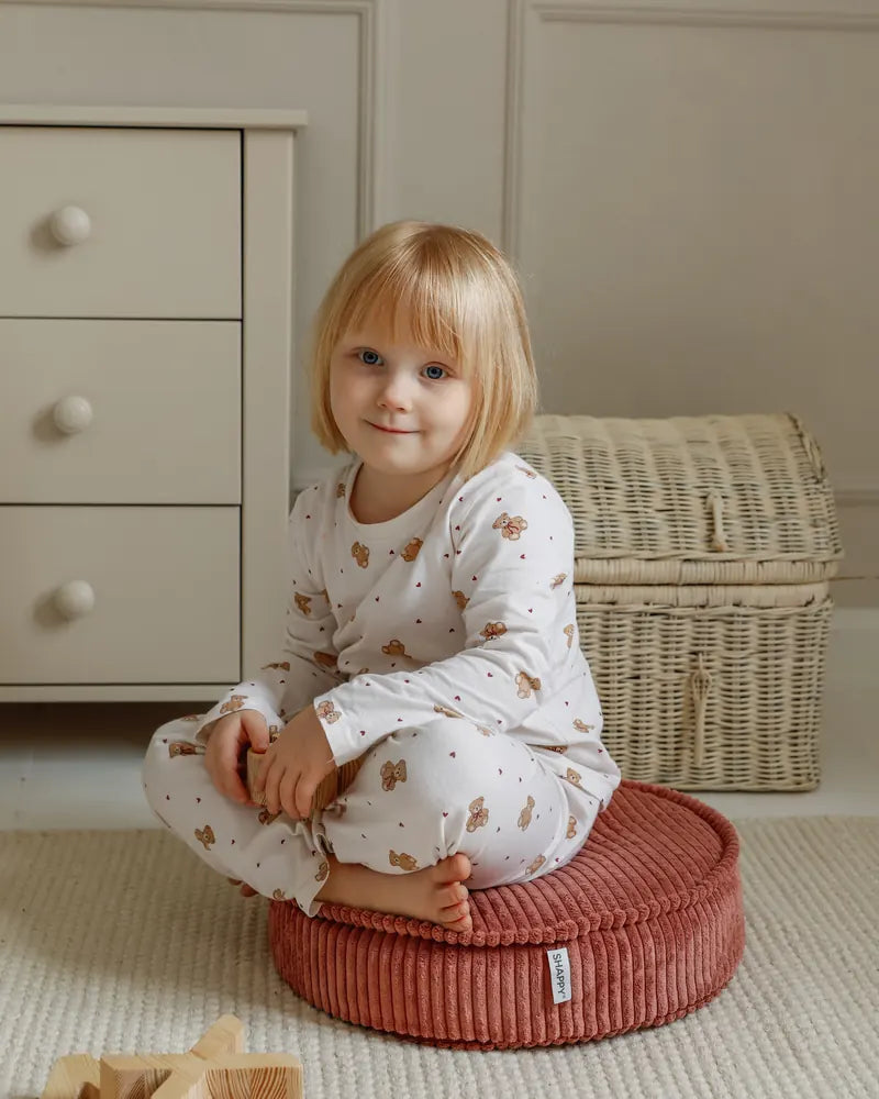 Dziecko siedzi na pufie Yuka Mini w kolorze Rose